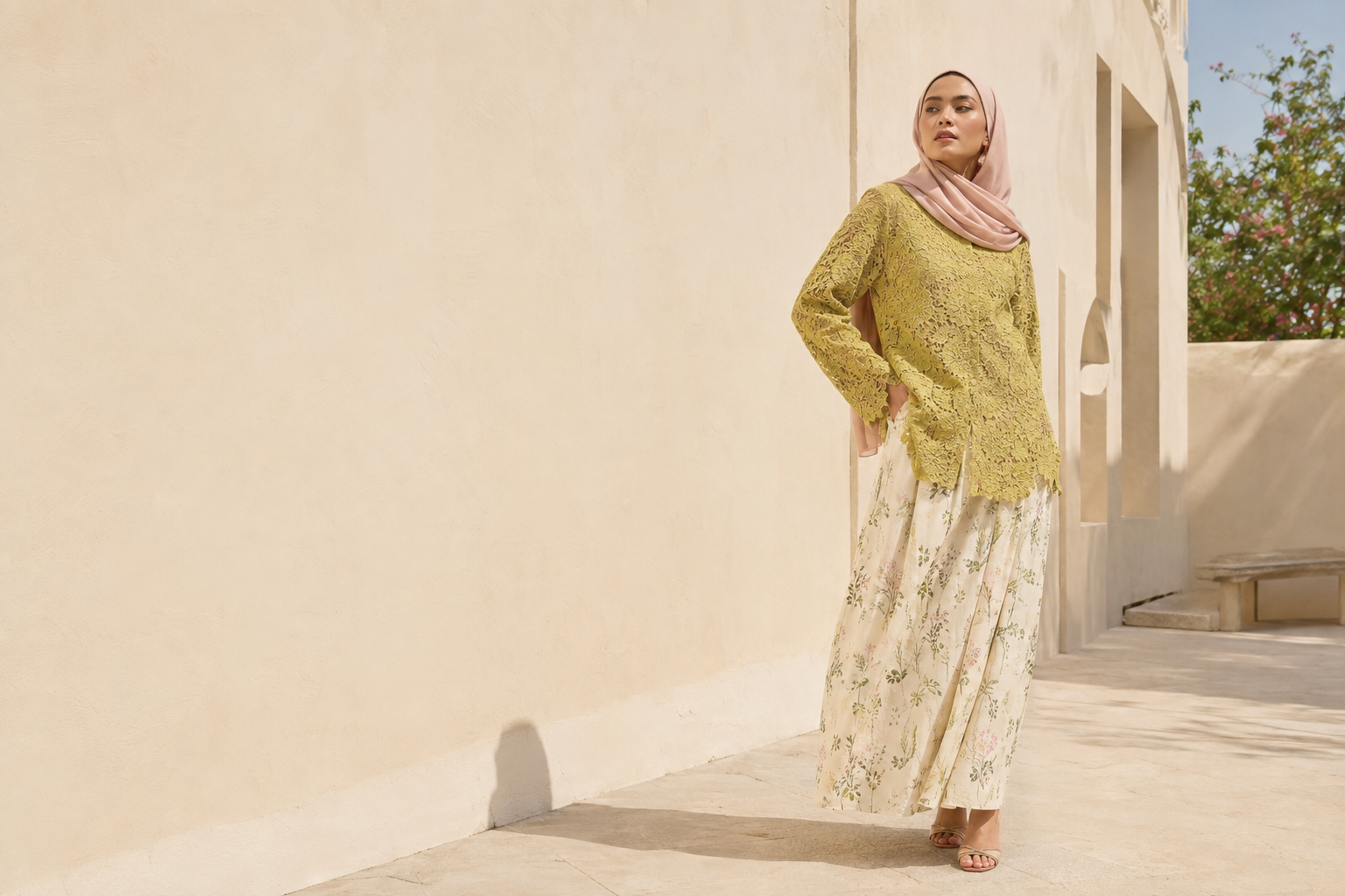 Editorial AI: model fiktif dengan hijab merah muda, blus zaitun, dan rok bermotif bunga di halaman bermandikan cahaya